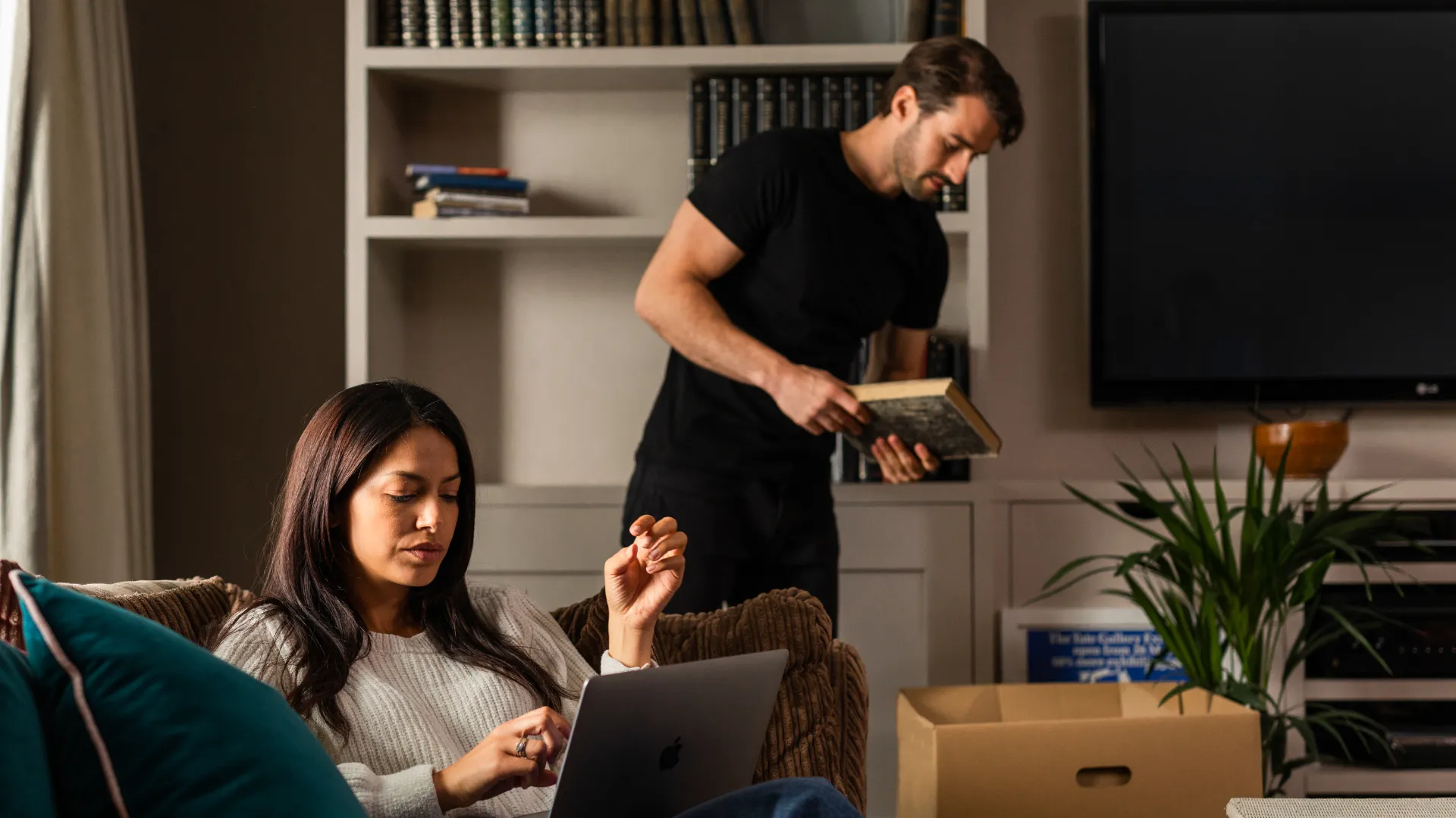 couple planning a move on a laptop whilst packing boxes