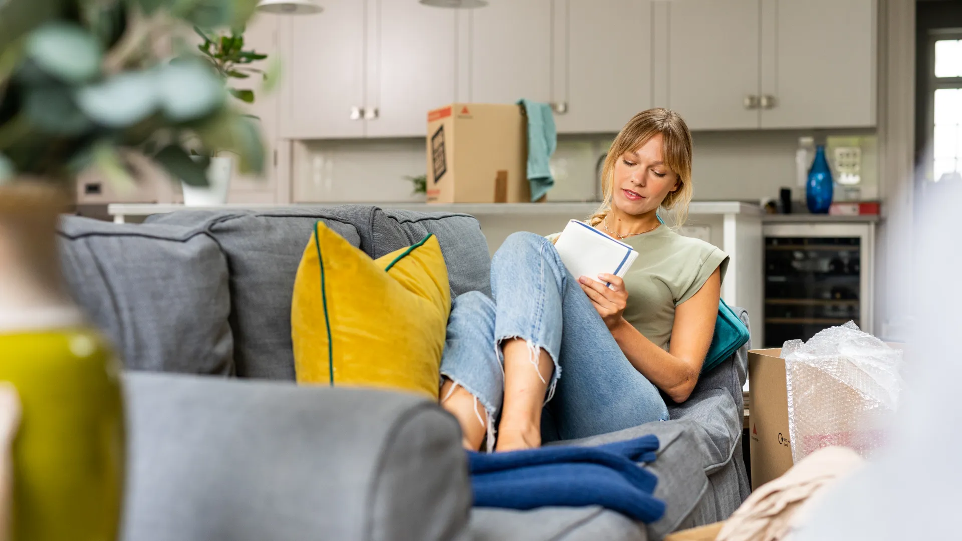 woman planning amongst boxes sat on sofa