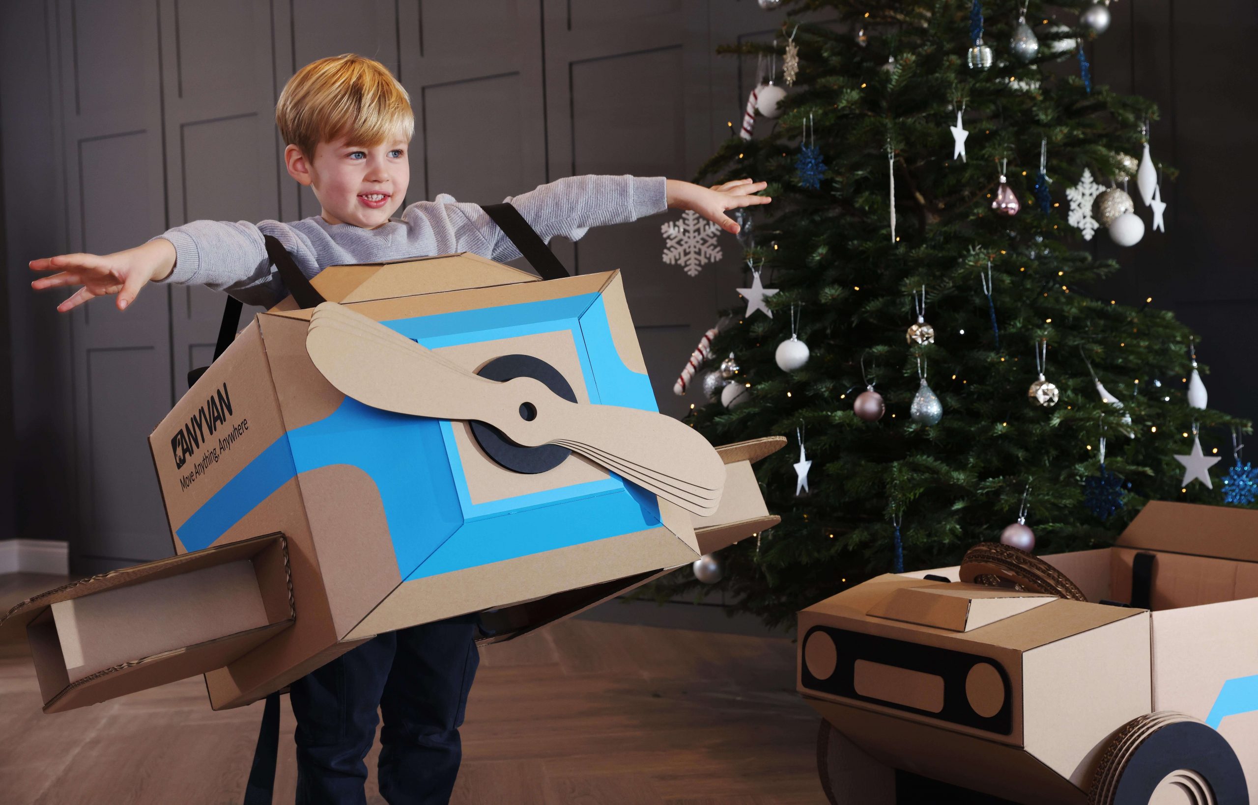 child in the anyvan box toy plane with a christmas tree behind them