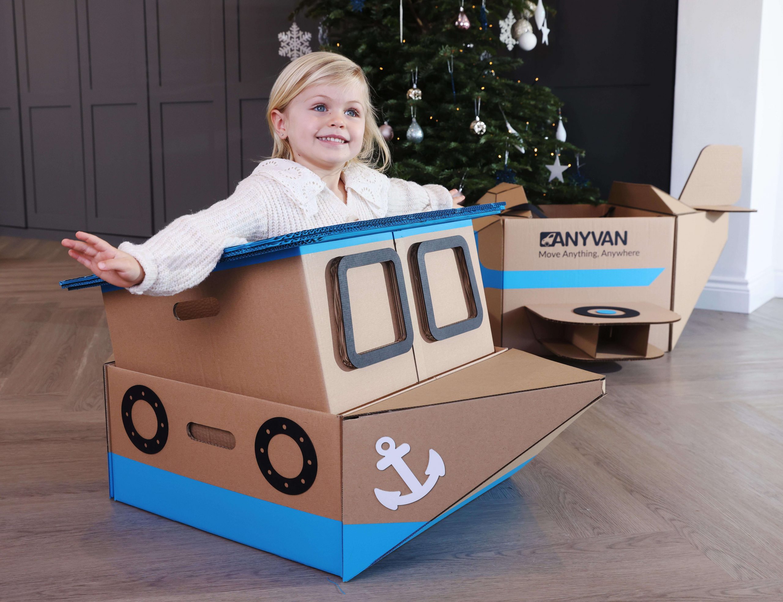 child in the anyvan box toys boat with a christmas tree and plane in the background
